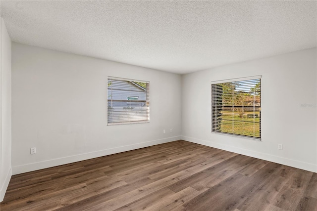 empty room featuring a wealth of natural light, baseboards, and wood finished floors