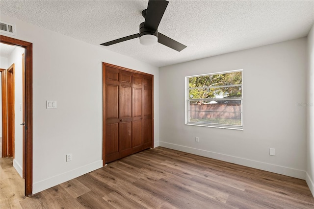 unfurnished bedroom featuring a closet, visible vents, baseboards, and wood finished floors