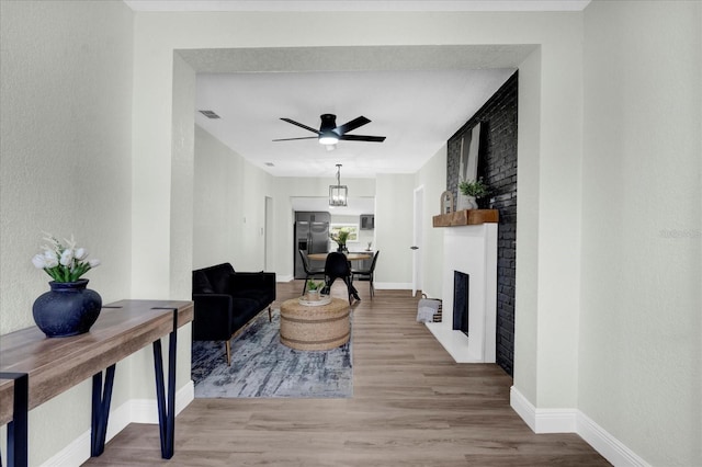 living area featuring baseboards, a fireplace, visible vents, and wood finished floors