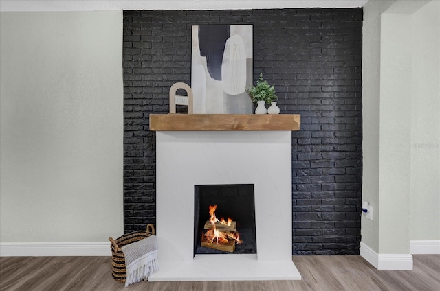 interior details with a lit fireplace, baseboards, and wood finished floors