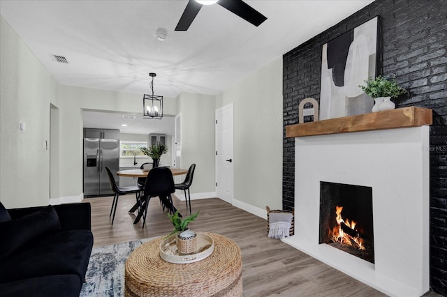 living area featuring a fireplace, wood finished floors, visible vents, and baseboards