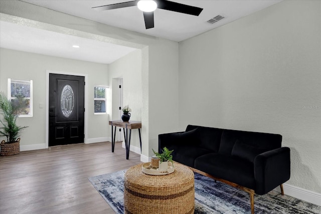 interior space featuring a ceiling fan, baseboards, visible vents, and wood finished floors