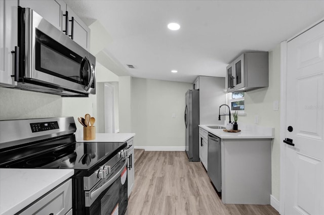 kitchen featuring visible vents, stainless steel appliances, light countertops, gray cabinetry, and a sink