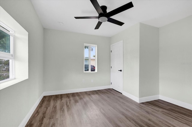 spare room featuring plenty of natural light, baseboards, and wood finished floors