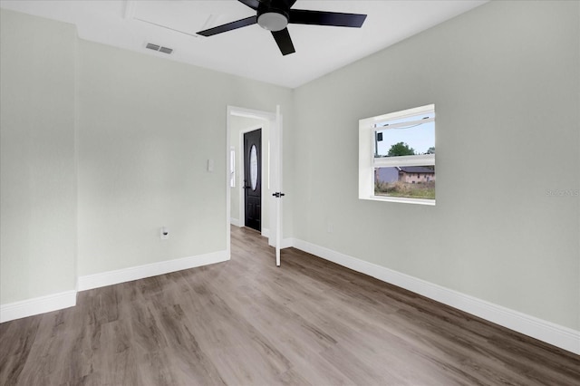 unfurnished room featuring a ceiling fan, visible vents, baseboards, and wood finished floors