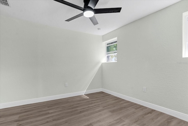 unfurnished room featuring baseboards, visible vents, ceiling fan, and wood finished floors