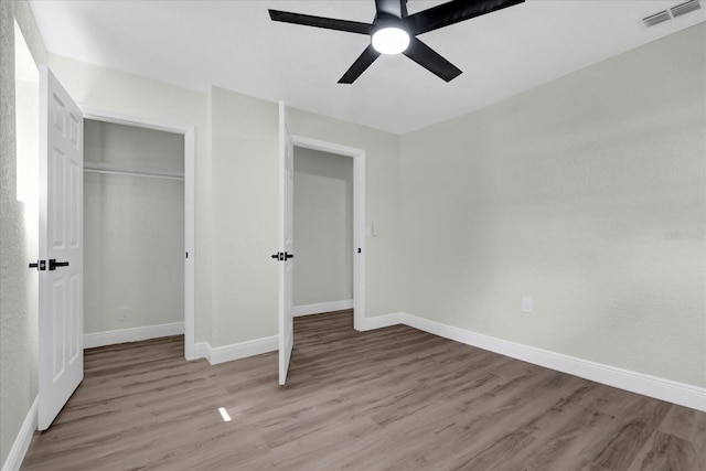 unfurnished bedroom with a closet, visible vents, baseboards, and wood finished floors