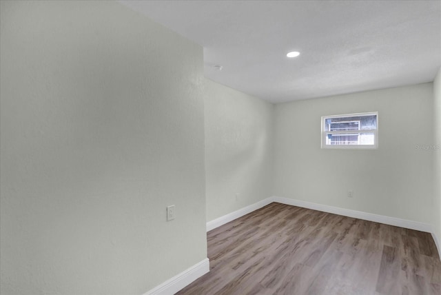 spare room featuring baseboards, wood finished floors, and recessed lighting