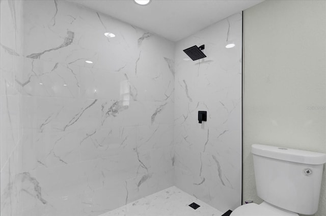 bathroom featuring a marble finish shower and toilet