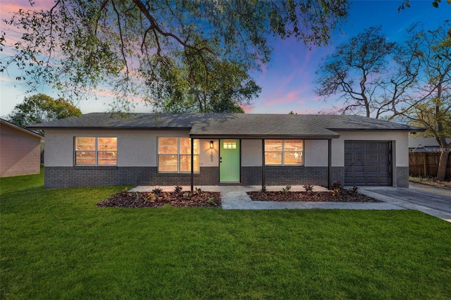 view of front facade with driveway, a garage, brick siding, a front lawn, and stucco siding