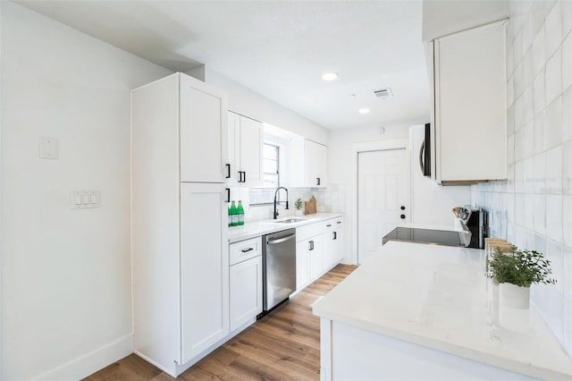 kitchen with visible vents, decorative backsplash, light wood-style flooring, stainless steel appliances, and a sink