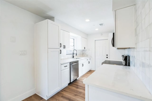 kitchen featuring stainless steel appliances, a sink, visible vents, backsplash, and light wood finished floors