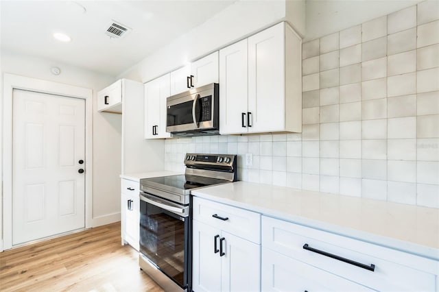 kitchen featuring stainless steel appliances, visible vents, light wood-style floors, light countertops, and tasteful backsplash