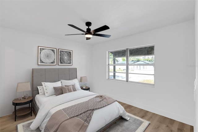 bedroom featuring ceiling fan, light wood-style flooring, and baseboards