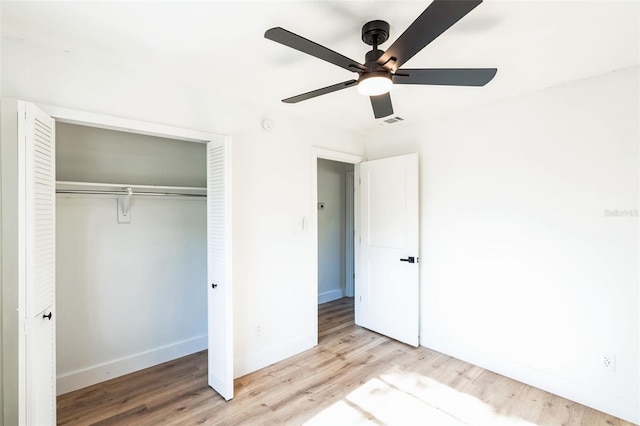 unfurnished bedroom with ceiling fan, wood finished floors, visible vents, baseboards, and a closet