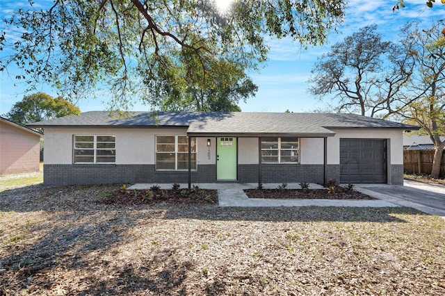 single story home with a garage, brick siding, fence, concrete driveway, and stucco siding