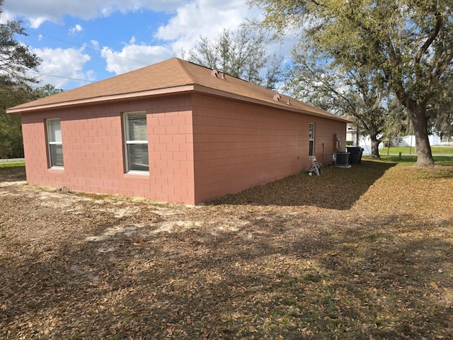 view of side of home with concrete block siding and central AC