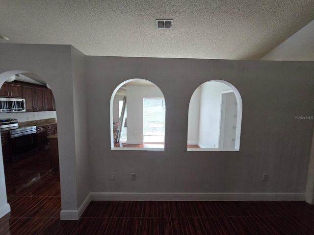 unfurnished room featuring a textured ceiling, visible vents, and baseboards