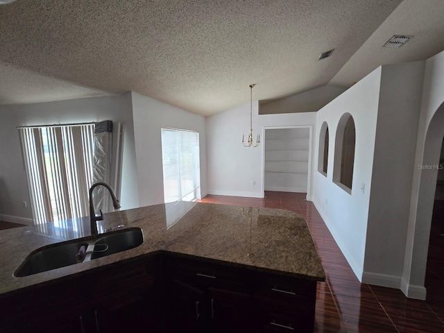 kitchen featuring lofted ceiling, visible vents, dark wood-type flooring, a sink, and a textured ceiling