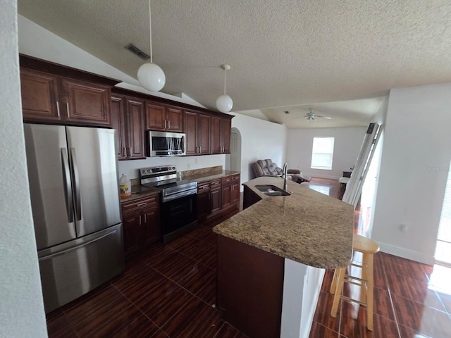 kitchen featuring arched walkways, a breakfast bar, stainless steel appliances, visible vents, and a sink