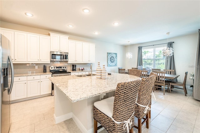 kitchen with white cabinets, light stone countertops, appliances with stainless steel finishes, and a kitchen breakfast bar