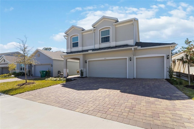 view of front of home featuring metal roof, decorative driveway, a standing seam roof, and stucco siding