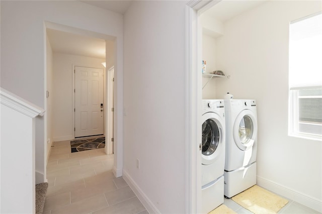 washroom with washer and dryer, laundry area, light tile patterned flooring, and baseboards