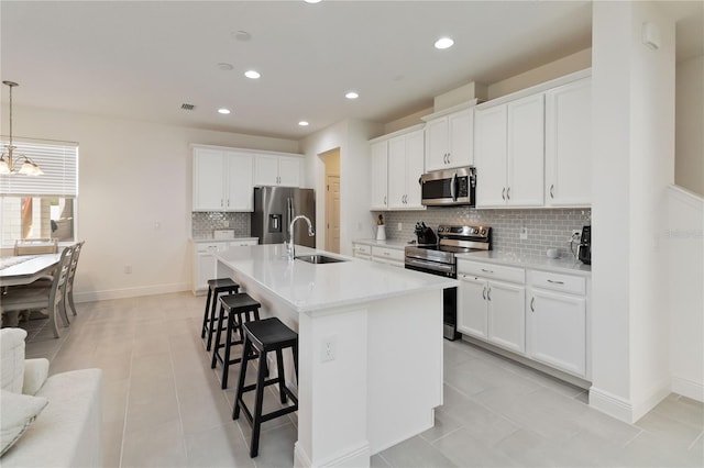 kitchen with an island with sink, a kitchen breakfast bar, light countertops, stainless steel appliances, and a sink