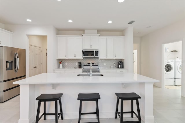 kitchen with stainless steel appliances, tasteful backsplash, washing machine and dryer, and a kitchen breakfast bar