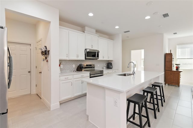 kitchen featuring tasteful backsplash, visible vents, a breakfast bar area, appliances with stainless steel finishes, and a sink