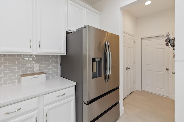 kitchen with stainless steel fridge, light stone counters, white cabinetry, backsplash, and recessed lighting