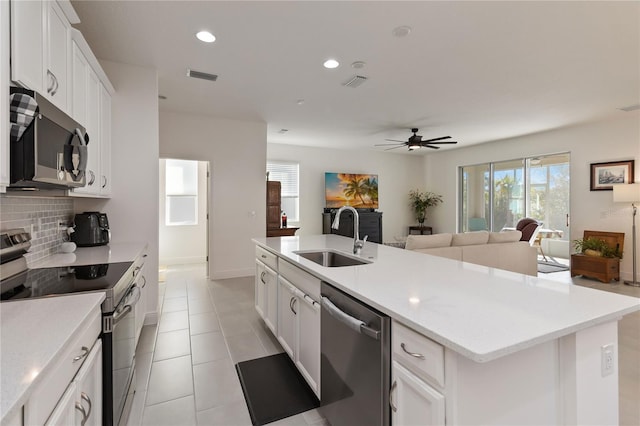 kitchen featuring tasteful backsplash, open floor plan, stainless steel appliances, a sink, and recessed lighting