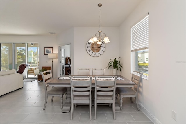 dining space with light tile patterned floors, baseboards, a wealth of natural light, and an inviting chandelier