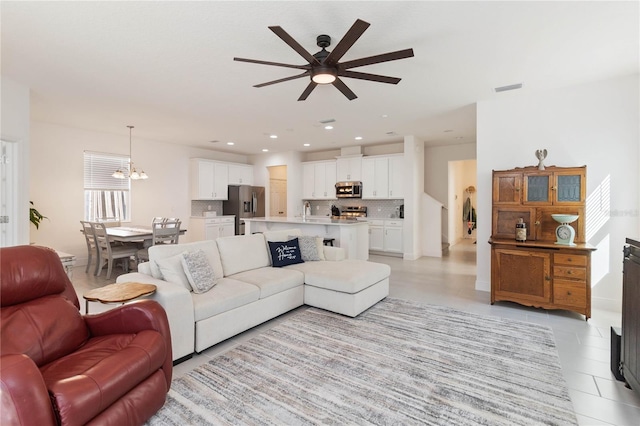 living room featuring light tile patterned floors, ceiling fan with notable chandelier, visible vents, and recessed lighting