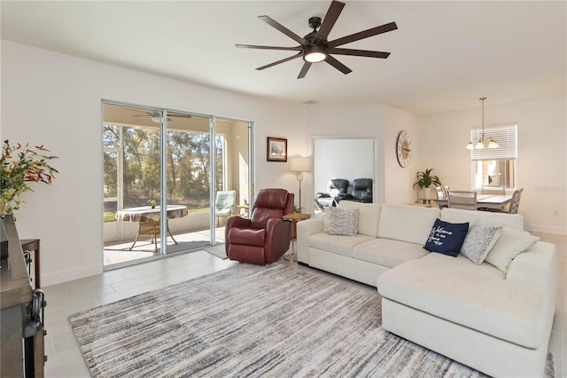 living area with ceiling fan with notable chandelier and baseboards