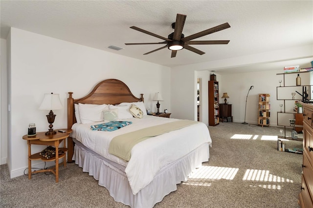 bedroom with light carpet, a textured ceiling, visible vents, and baseboards