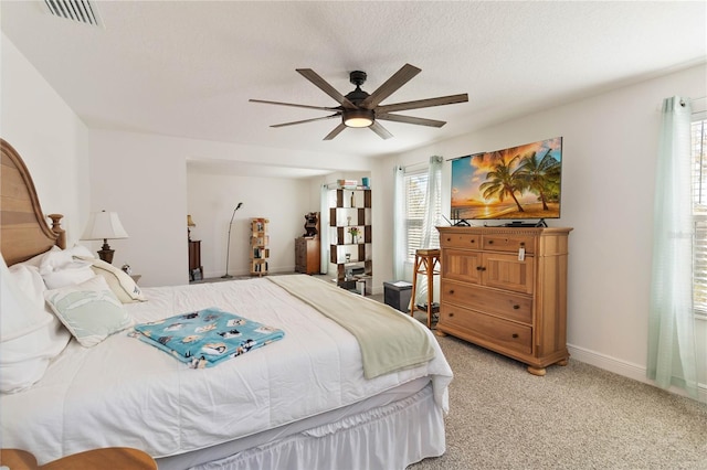 bedroom featuring a textured ceiling, carpet flooring, visible vents, baseboards, and a ceiling fan