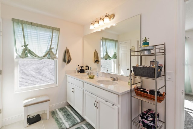 full bathroom with double vanity, baseboards, and a sink