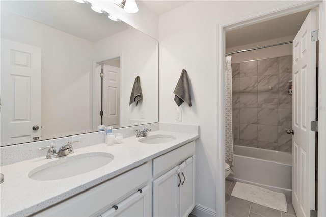 bathroom with double vanity, toilet, a sink, and tile patterned floors