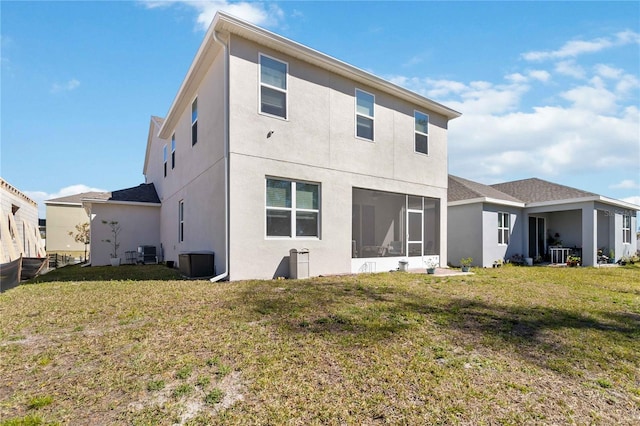 rear view of property featuring a sunroom, central AC, a lawn, and stucco siding