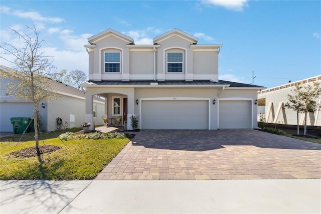 view of front facade with a garage, metal roof, decorative driveway, and a standing seam roof