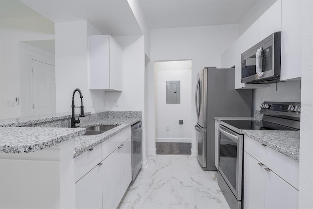 kitchen featuring appliances with stainless steel finishes, light stone countertops, marble finish floor, white cabinetry, and a sink