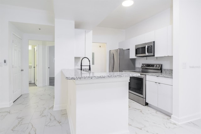 kitchen with baseboards, marble finish floor, appliances with stainless steel finishes, and white cabinets