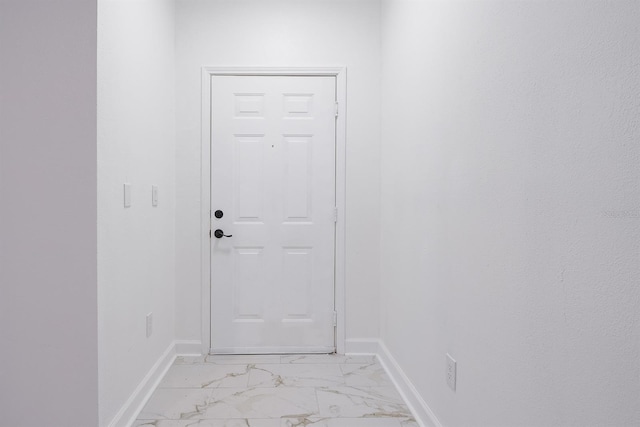 entryway with marble finish floor and baseboards