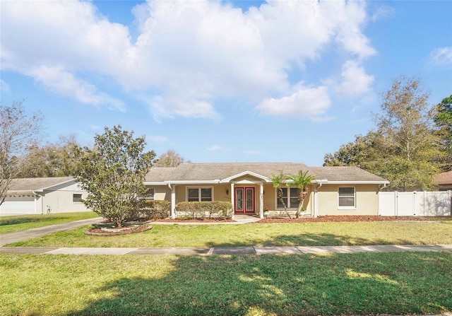 ranch-style house featuring driveway, fence, french doors, a front yard, and stucco siding