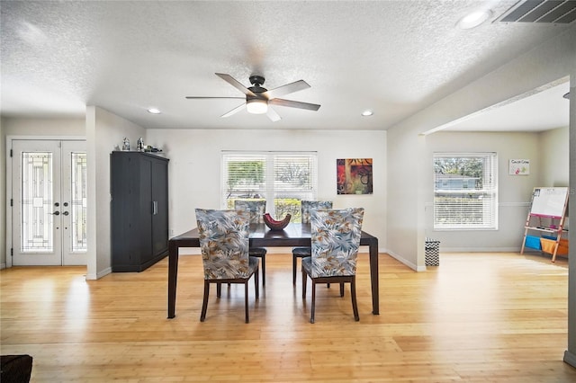 dining room with a wealth of natural light, french doors, visible vents, and light wood finished floors