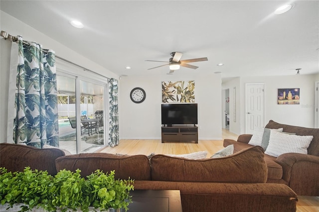 living room featuring baseboards, light wood-type flooring, a ceiling fan, and recessed lighting