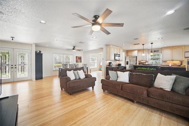 living room with a textured ceiling, french doors, light wood finished floors, and recessed lighting