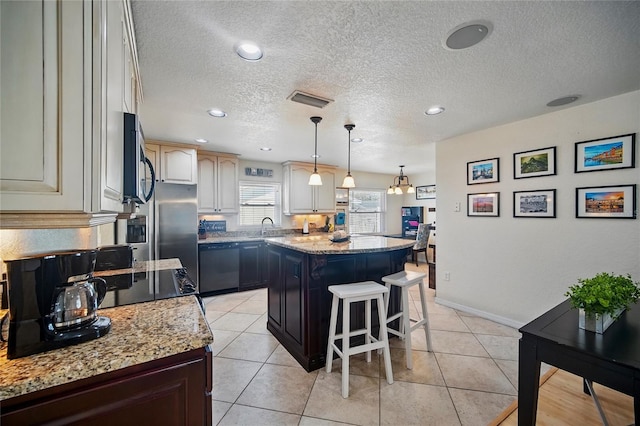 kitchen featuring a center island, stainless steel microwave, visible vents, dishwasher, and a kitchen breakfast bar