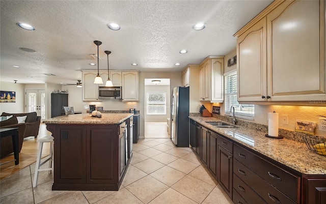 kitchen featuring recessed lighting, stainless steel appliances, a kitchen island, a sink, and open floor plan